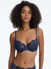 Woman wearing a navy blue lace bra and panties set on a white background