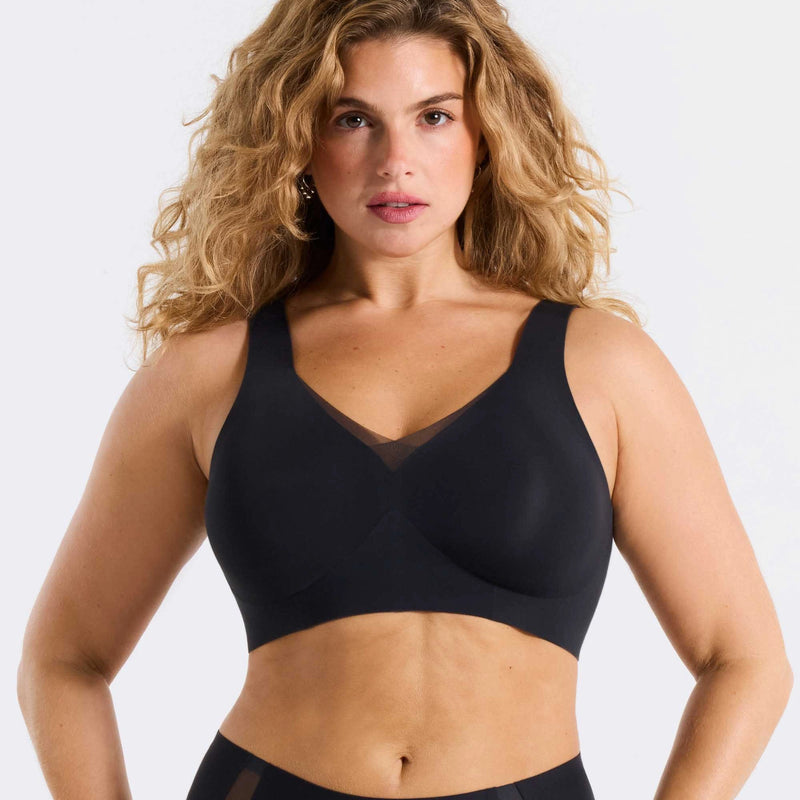 Woman wearing a black bra against a white background