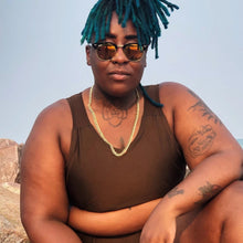 Load image into Gallery viewer, A person wearing sunglasses with blue dreadlocks is crouching down and wearing a dark brown binder
