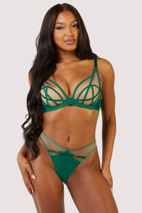 A woman with long black hair wears a green cage bra with a matching thong